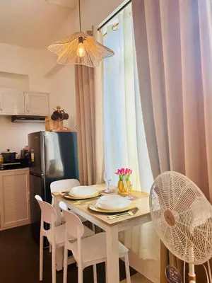 a dining room table with white chairs and a fan at Budget Friendly Staycation walking distance to Venice Mall with Netflix and Wifi in Manila