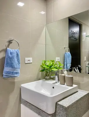 a bathroom with a white sink and a mirror at Cozy place across Mitsukoshi Mall in Manila