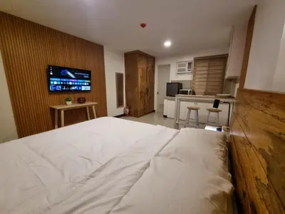 a bedroom with a large white bed and a kitchen at Flat 35, Unit F in Manila