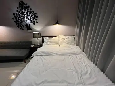 a large white bed in a room with a couch at Cozy Makati Condo Getaway with balcony in Manila
