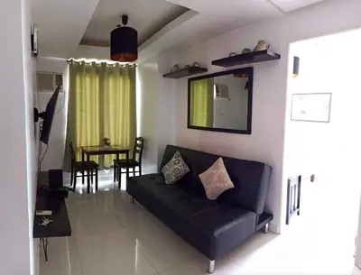 a living room with a black couch and a table at Explore Manila, Trendy 1BR unit in Prime Location in Manila