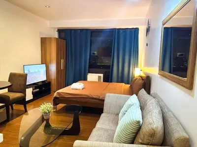 a bedroom with a bed and a couch and a table at Spacious Unit in Gramercy Makati in Manila