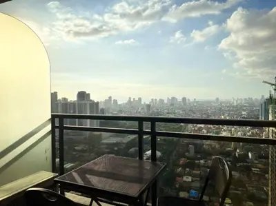 a table and chairs on a balcony with a city at Spacious Unit in Gramercy Makati in Manila