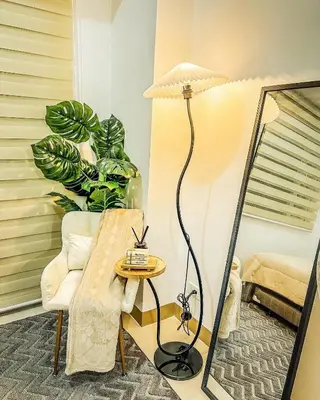 a floor lamp in a living room with a chair and a table at Natural Haven at South in Manila