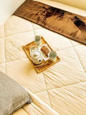 a tray with three cups and food on a bed at Natural Haven at South in Manila