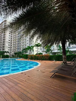 a pool with chairs and a palm tree next to a building at Natural Haven at South in Manila