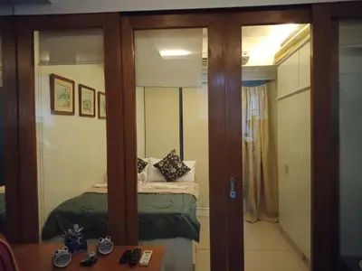 a small bedroom with a bed and a mirror at Jericho's Place in Manila