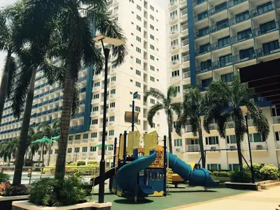a playground in front of a large building with palm trees at Jericho's Place in Manila