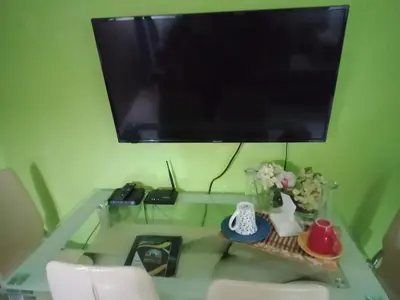 a glass table with a television on a green wall at Jericho's Place in Manila