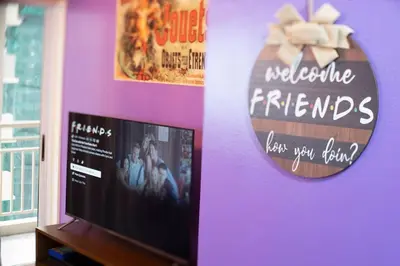 a tv on a purple wall with a welcome friends sign at The One with Purple Apartment in Manila