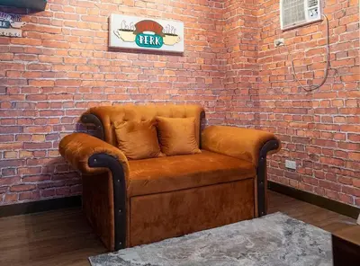 a brown couch sitting against a brick wall at The One with Purple Apartment in Manila