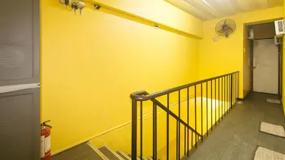 a hallway with a yellow wall with a stair railing at RedDoorz at LYOTO Bed and Breakfast near NAIA Terminal in Manila