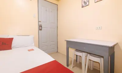 a bedroom with a bed and a table and stools at RedDoorz at LYOTO Bed and Breakfast near NAIA Terminal in Manila