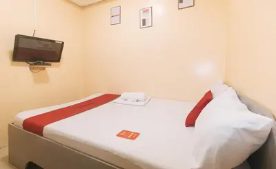 a small room with a bed with a tv on the wall at RedDoorz at LYOTO Bed and Breakfast near NAIA Terminal in Manila