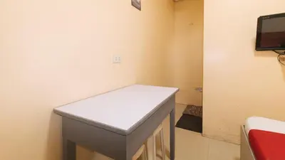 a room with a table and a tv on the wall at RedDoorz at LYOTO Bed and Breakfast near NAIA Terminal in Manila