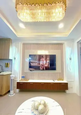 a living room with a chandelier and a tv on the wall at 1BR Balcony Luxury Condo Shore 2 Near MOA & NAIA in Manila