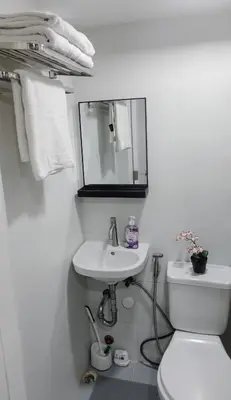 a white bathroom with a toilet and a sink at Modern Condo for 6, with Kitchen, Wi-Fi & Netflix, Near MRT Boni in Manila