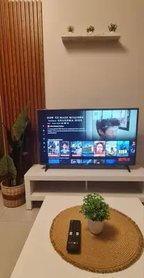 a television sitting on a table with a remote control at 1BR with Balcony Condo accross NAIA T3 in Manila