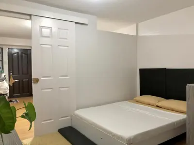 a bedroom with a bed and a white wall at Metro Suites in Anabu Primero
