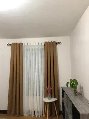 a room with a curtain and a table with a chair at Metro Suites in Anabu Primero