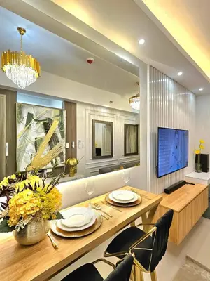 a dining room with a table and chairs and a television at Skyport Luxe in Manila