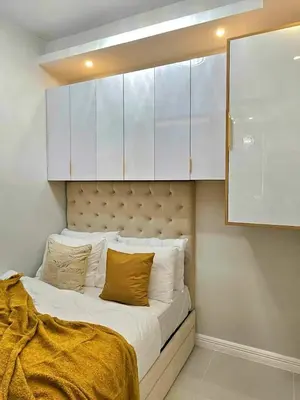 a bed with white cabinets and yellow pillows on it at Skyport Luxe in Manila