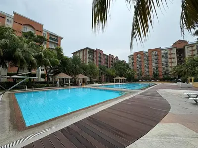 a large swimming pool with palm trees and buildings at Kalizta Suites in Manila