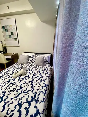 a bedroom with a bed with a blue and white comforter at Ikigai Charlie Makati Condo Premium Comfort & Luxury in Manila