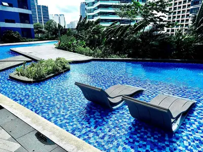 a swimming pool with two chairs in the middle of it at Ikigai Charlie Makati Condo Premium Comfort & Luxury in Manila