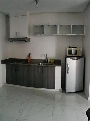 a kitchen with a sink and a refrigerator at Explore Manila Trendy 1BR unit in Birch Tower in Manila