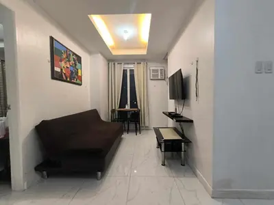 a living room with a couch and a television at Explore Manila Trendy 1BR unit in Birch Tower in Manila