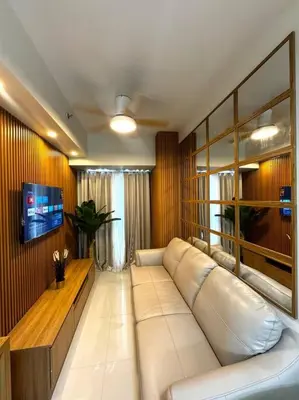 a living room with a white couch and a tv at Shore 3 katkat staycation in Manila