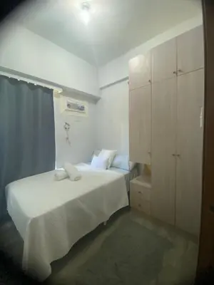 a small bedroom with a bed and a cabinet at Tiaras Luxury Condotel in Manila