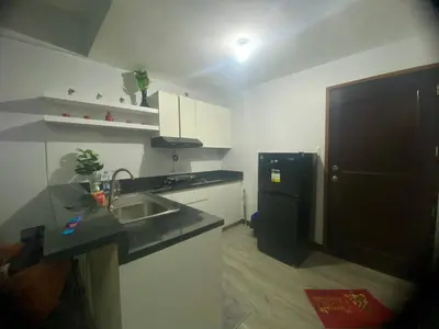 a kitchen with a sink and a black refrigerator at Tiaras Luxury Condotel in Manila