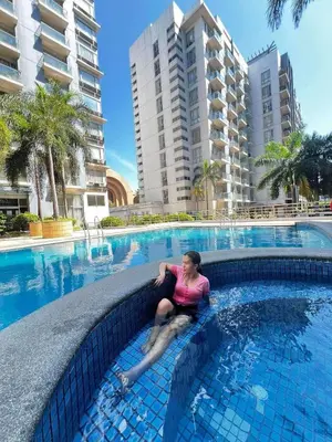 a woman sitting in the water in a swimming pool at One palm tree villas &Two palm tree villas in Manila