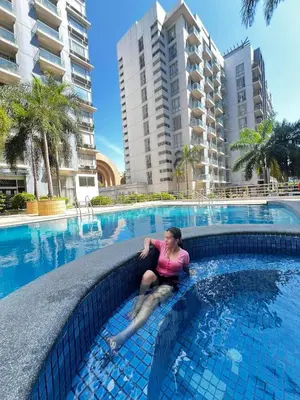 a woman sitting in the water in a swimming pool at One palm tree villas &Two palm tree villas in Manila