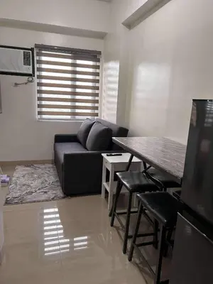 a living room with a black couch and a table at Newly build Condo Minimalist Charm in Manila