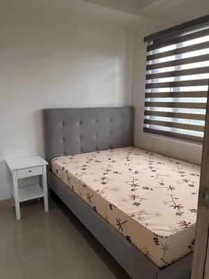 a bedroom with a bed and a window and a table at Newly build Condo Minimalist Charm in Manila