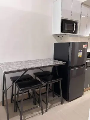 a kitchen with a counter with stools and a refrigerator at Newly build Condo Minimalist Charm in Manila