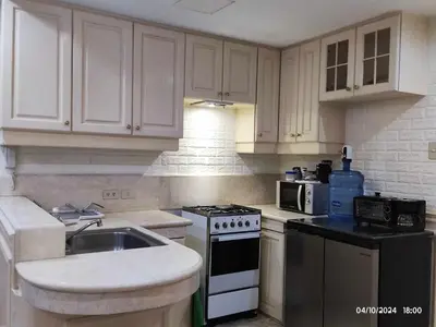 a kitchen with white cabinets and a stove and a sink at Condo With Balcony And Bayview In Malate, Manila in Manila