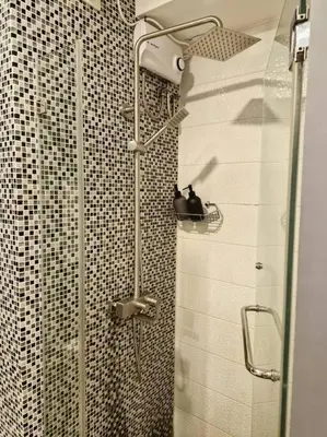 a shower with a glass door in a bathroom at Cozy retreat w Balcony, Netflix, 100 mbps internet, Pool, near BGC in Manila