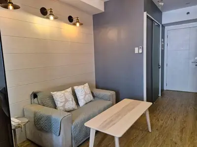 a living room with a couch and a table at Cozy retreat w Balcony, Netflix, 100 mbps internet, Pool, near BGC in Manila