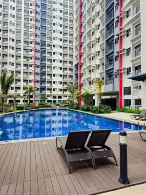 a swimming pool with a chair in front of some buildings at Bloom Residences Relaxation Escape in Manila