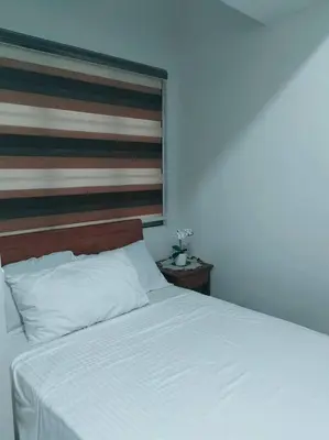 a bedroom with a white bed with a wooden headboard at 2 Bedroom near MOA S Residences in Manila