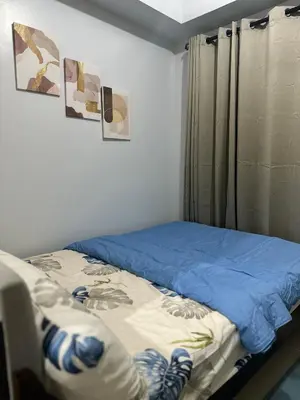 a small bedroom with a bed with blue sheets at Sea Residences by Richnell's Staycation 