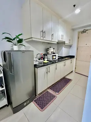 a kitchen with white cabinets and a stainless steel refrigerator at Sea Residences by Richnell's Staycation 