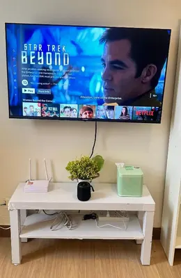 a tv hanging on a wall with a white table at Enchantress Abode in Trece Martires
