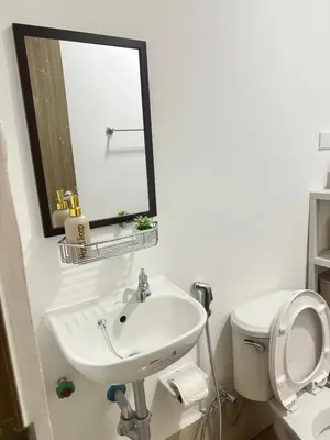 a bathroom with a sink and a mirror and a toilet at Enchantress Abode in Trece Martires