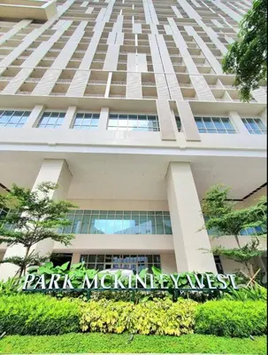 a tall white building with a sign in front of it at 10G Cozy Condo at Park McKinley West near Venice Mall in Manila