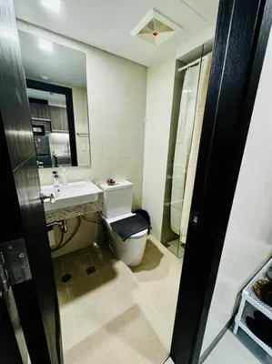 a bathroom with a toilet and a sink and a shower at 10G Cozy Condo at Park McKinley West near Venice Mall in Manila